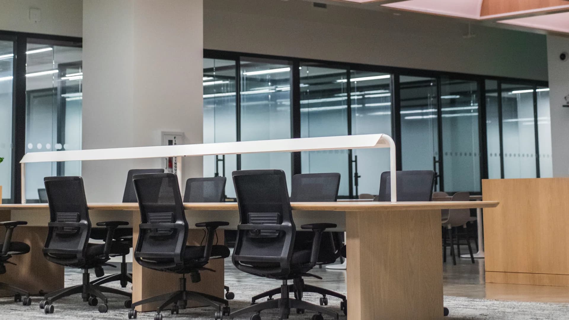 Oficina corporativa moderna con amplios ventanales y puestos de trabajo iluminados